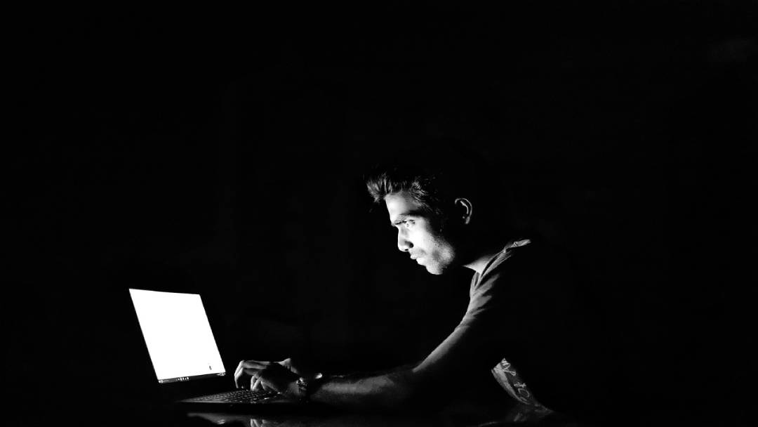 Man sitting at the computer in dark hacking