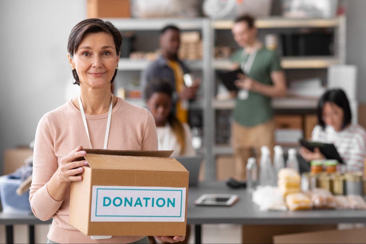 a woman standing holding a donation box