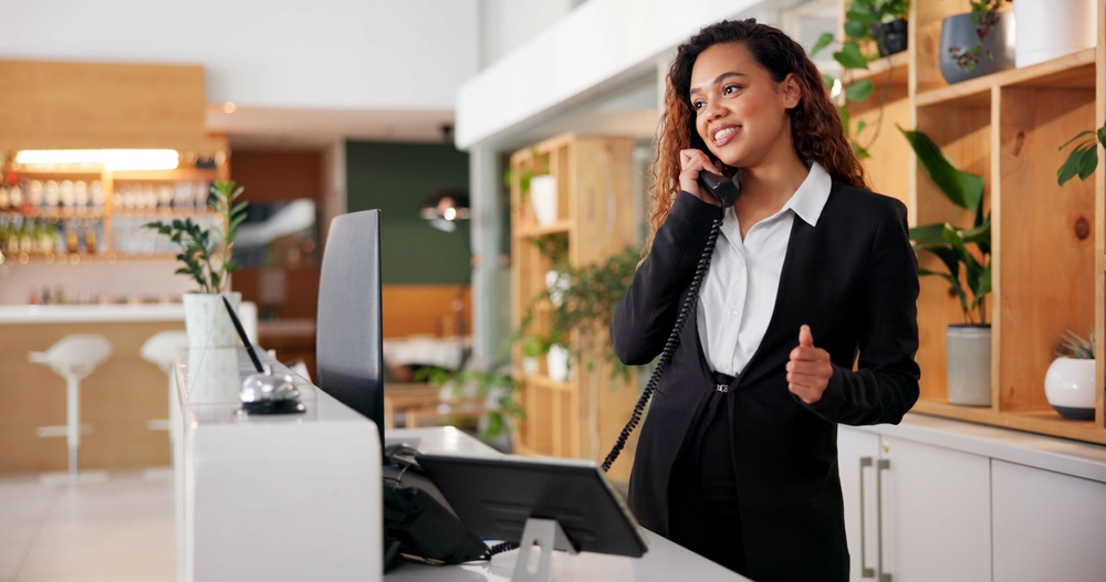 Hotel receptionist using the best hotel phone systems with Clear Clouds to manage guest reservations and front desk communication.