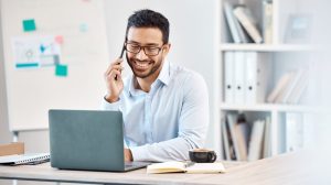 Business professional smiling while speaking on the phone in an office representing Canadian companies exploring Zoom Phone alternatives for unified communication.