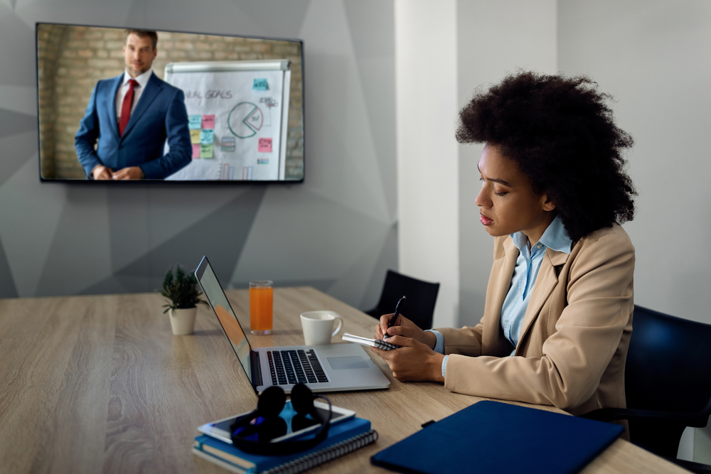Canadian business professional exploring whether SE Telecom can Microsoft Teams replace a phone system during a hybrid video call in a modern boardroom