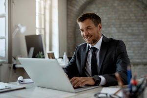 Canadian IT decision-maker smiling while reviewing telecommunications Canada costs with SE Telecom on laptop in modern office