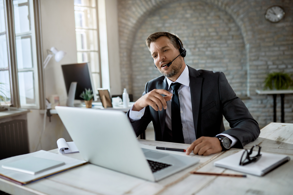 Canadian enterprise professional on SE Telecom telecommunications Canada call reviewing UCaaS platform options on laptop in modern workspace
