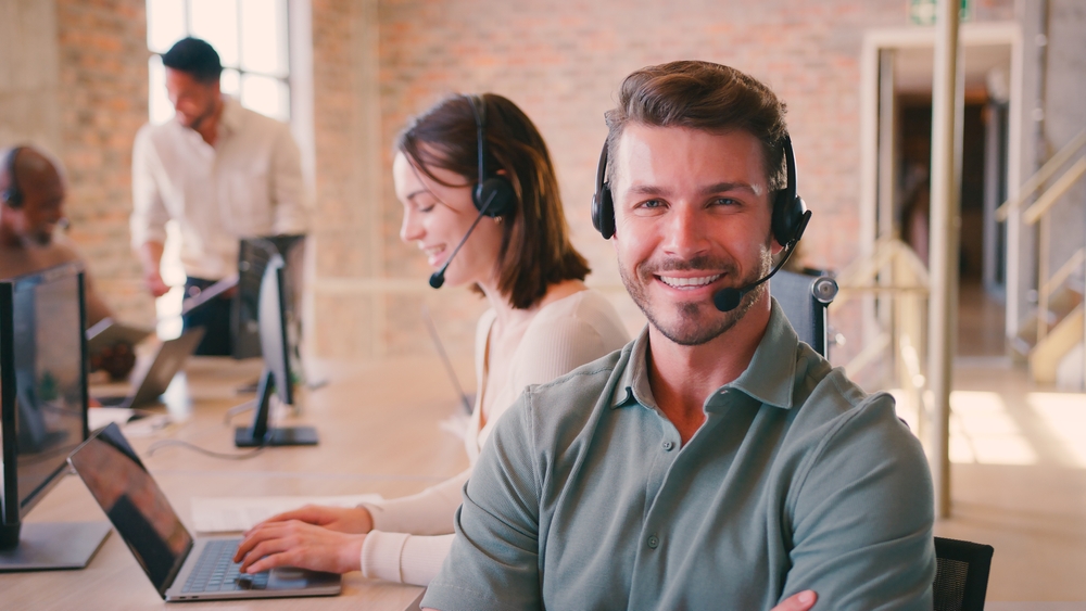 Manitoba organization professional smiling on headset using SE Telecom VoIP Winnipeg cloud platform on laptop in a modern open office