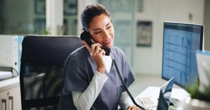 Woman talking on phone at a hospital front desk