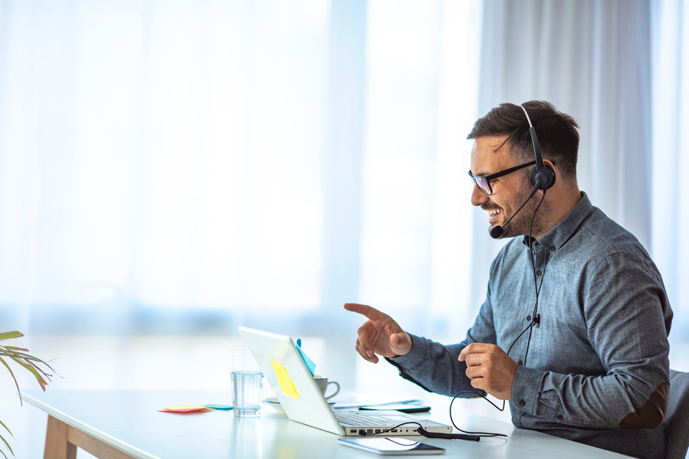 SE Telecom Canadian professional working on telephone for VoIP deployment on laptop with headset in a modern Canadian office environment