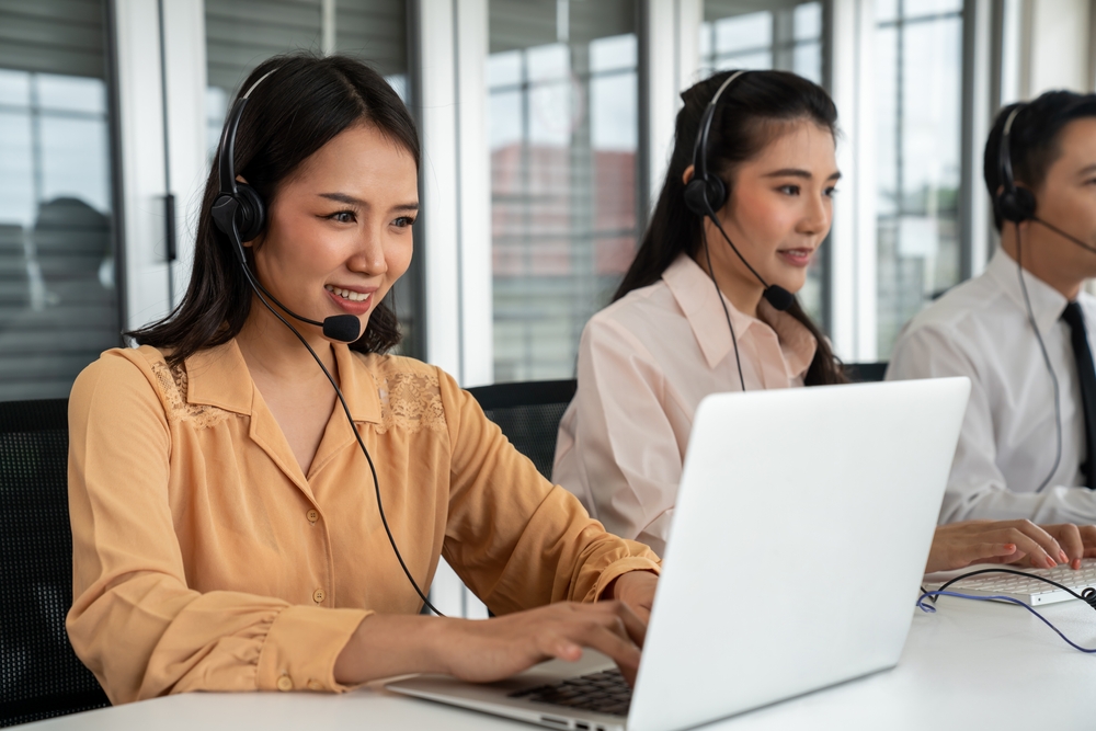 Winnipeg organization professional using SE Telecom VoIP phone Winnipeg platform on headset and laptop in a modern office environment
