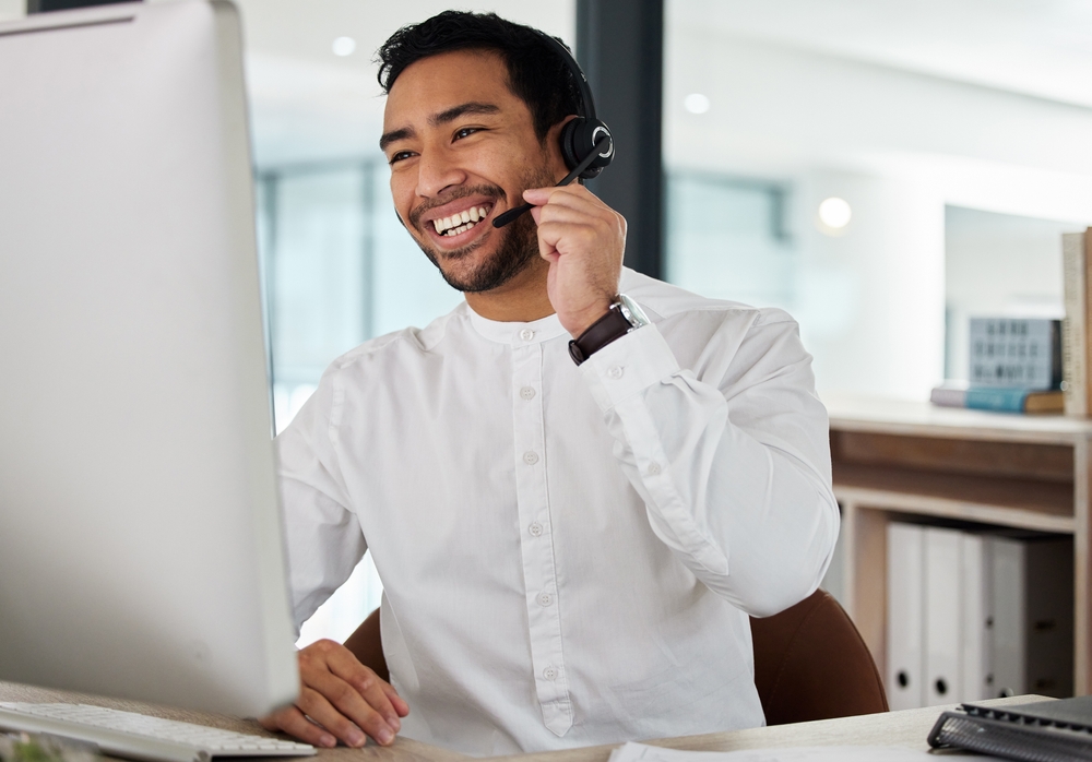 Office employee speaking with customers through a headset in a modern workplace supported by VoIP Halifax business phone solutions.
