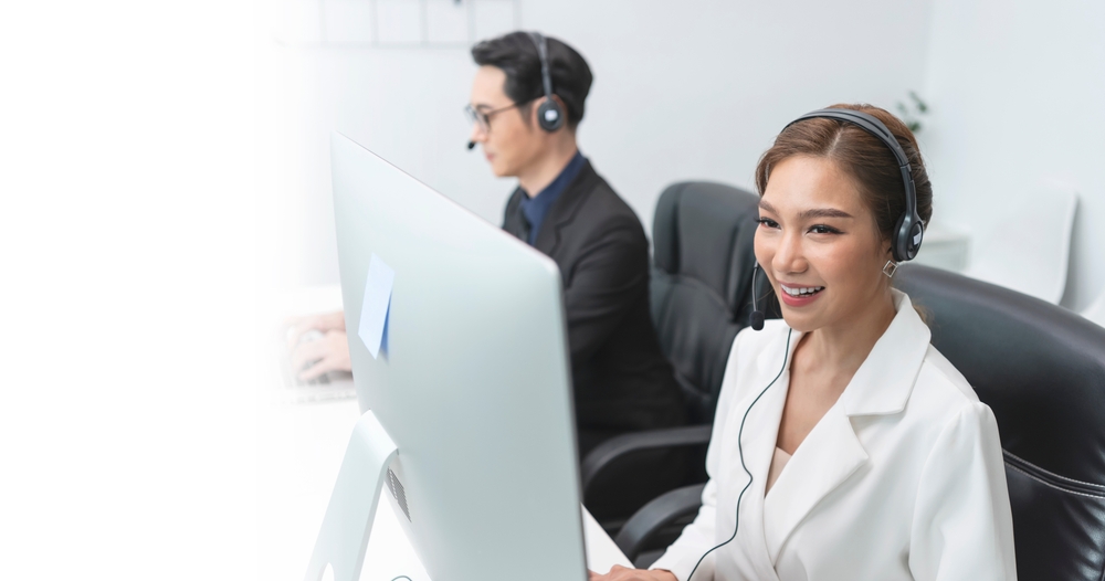 Modern office worker managing customer support calls with a headset and VoiP Hamilton communication technology.