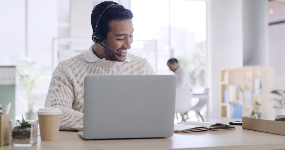 Office employee speaking with customers through a headset in a modern workplace supported by VoIP Surrey phone solutions.
