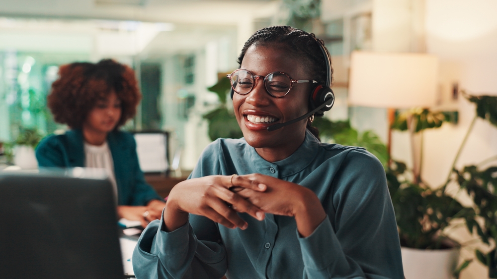 Office employee comparing VoIP service providers on a laptop during a business call