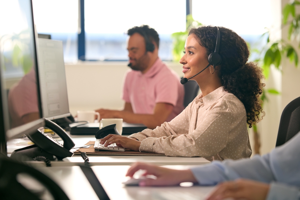 Office employee wearing a headset while working on a cloud communications platform