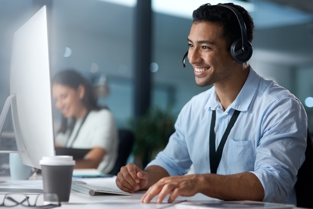 Business professional using a headset to manage unified communications solutions at their desk
