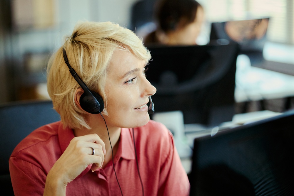 IT manager wearing a headset testing a new business phone service setup at a desk with a laptop