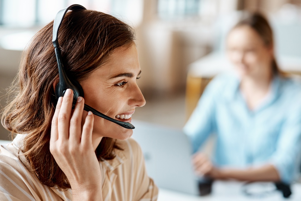 Customer service agent in a headset reviewing call queue data on a hosted VoIP dashboard
