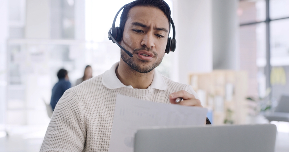 IT manager wearing a headset testing desk phones during a multi-site hosted VoIP rollout
